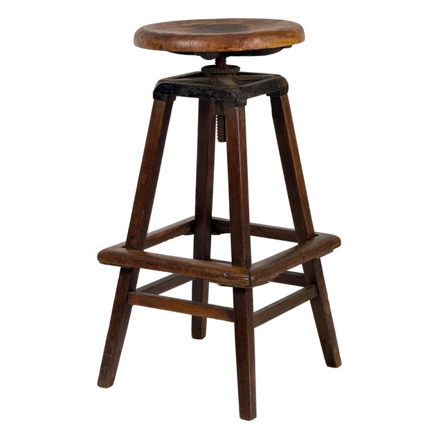 Antique 1910s industrial draftsman stool with a round wood seat, cast iron swivel adjustment, and tapered wood base with...