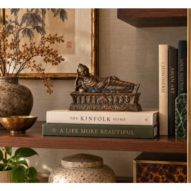 Striking vintage bronze sculpture depicting a reclining Buddha in a serene resting pose atop an elaborately decorated...
