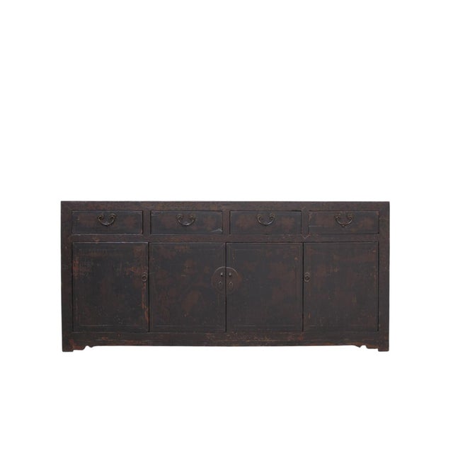 Dating to circa 1926, this antique Chinese sideboard has a rich dark brown finish, beautifully aged patina, and layers of...