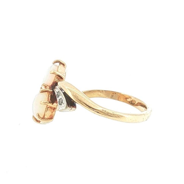 A Mid-century 14k gold ring featuring opals and diamonds in an offset style. The opals are white in color. Accented with...