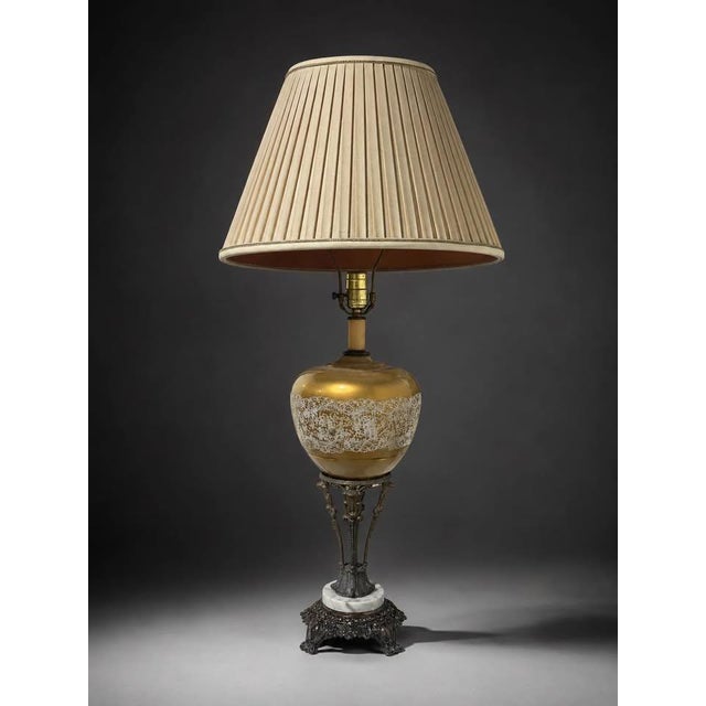A vintage-style ornate table lamp featuring a warm gold-toned glass body, intricate decorative patterning, antique bronze-...