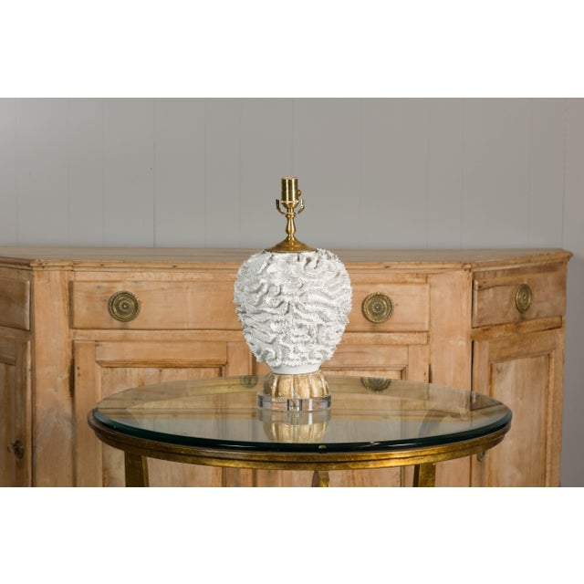 A Midcentury Italian white pottery table lamp with textured body and carved gilt wood base on round lucite. Emanating an...