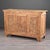 A three-door oak sideboard in natural, bare-wood finish, carved with Art Deco motifs. A central sunburst and wheat sheaf...
