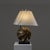Table lamp with a painted wooden pedestal supporting a spherical ceramic base decorated with golden highlights reminiscent...