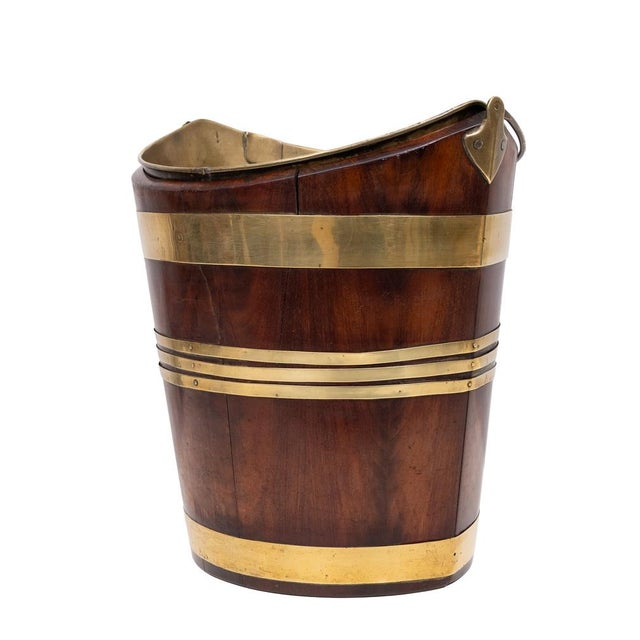 A 19th century Dutch boat shaped bucket with coopered mahogany staves bound with two wide and three narrow brass bands,...