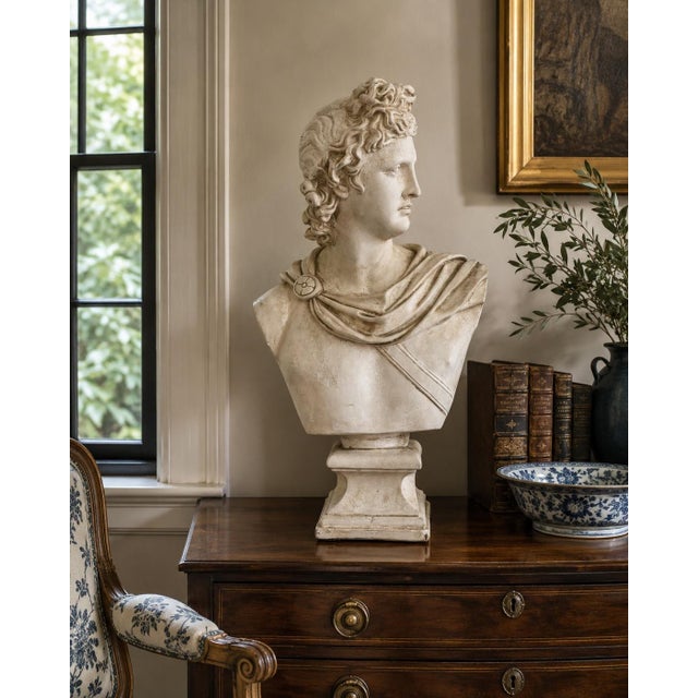A large neoclassical plaster bust after the celebrated Apollo Belvedere, modeled with the god’s idealized profile,...