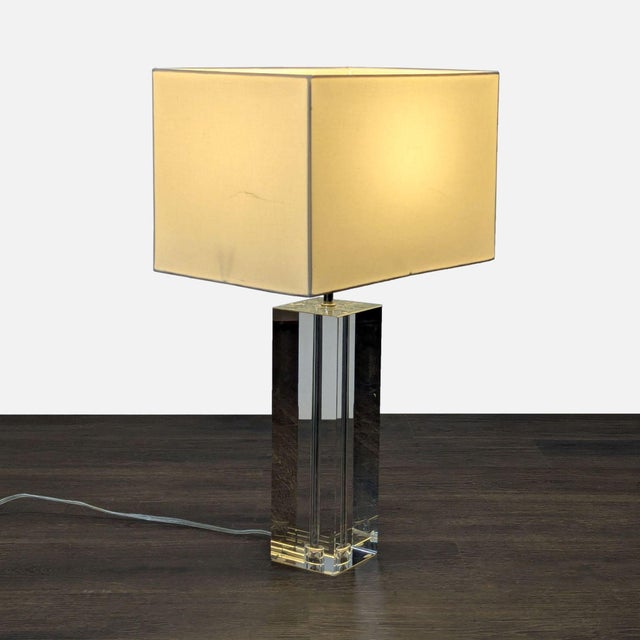 This Room & Board table lamp has a clear crystal base and a simple square fabric shade. Its clean and modern design can...