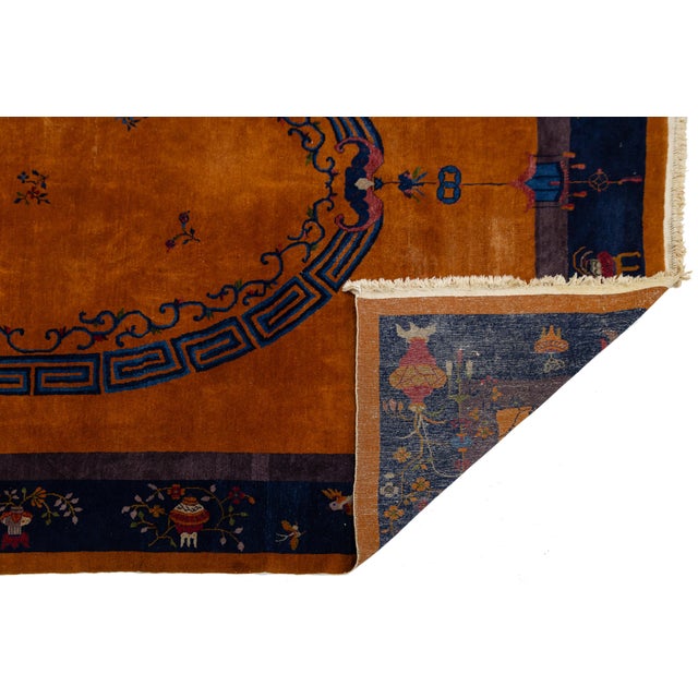This striking antique Chinese wool rug showcases a vibrant mandarin orange field typical of the Art Deco movement. It...