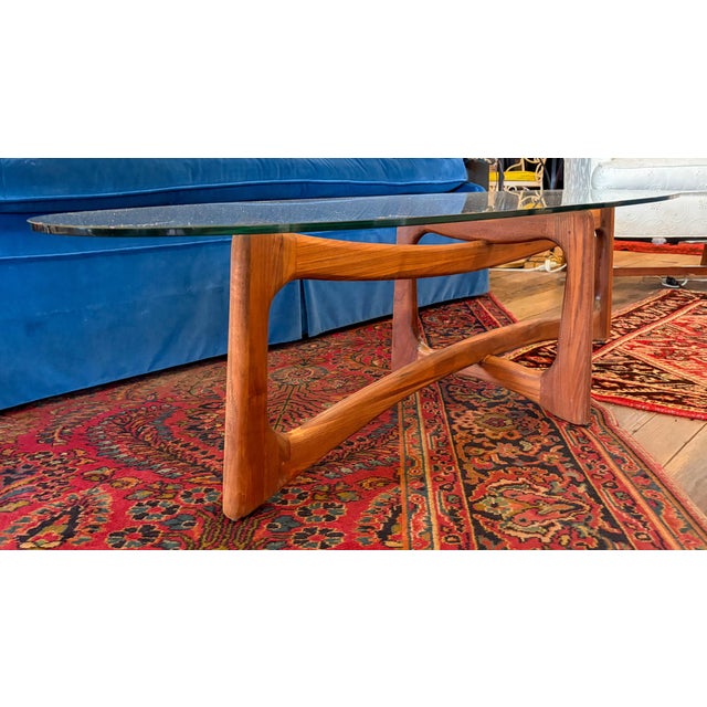 Stunning example of Mid Century Modern design and innovation. This oval, glass top table features a refinished, walnut...