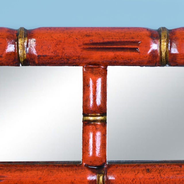 A faux bamboo mirror in red and gold with a Greek key border — chinoiserie and classical motifs in one glamorous frame....