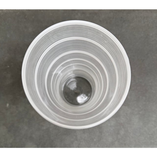Hour glass shaped glass vase with white stripes designed by Ingegerd Raman for Orrefors, Sweden. There is an acid etched...