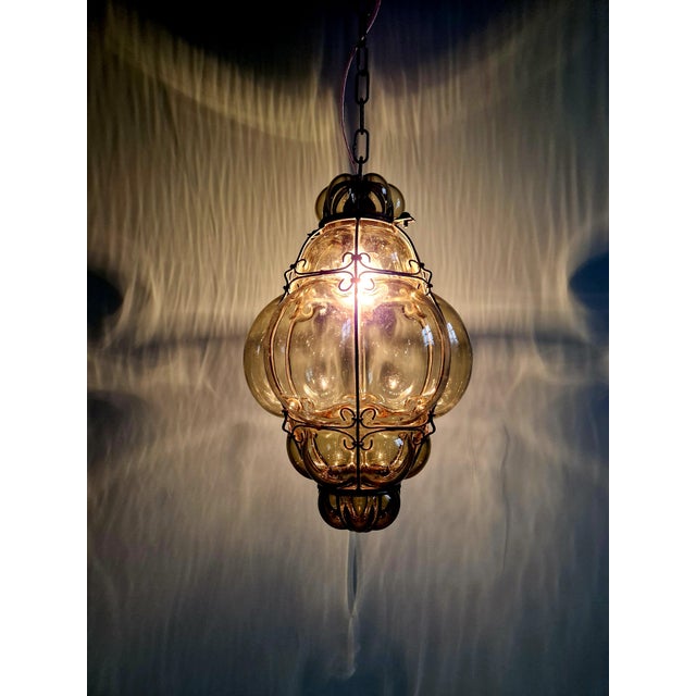 Venetian pendant light in green blown glass enclosed in a forged metal structure, dating from the mid-20th century. It has...