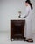 This side cabinet carries genuine presence, its dark walnut, single door, open shelf immediately setting the tone for the...