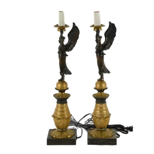 A dramatic pair of neoclassical revival figural table lamps, dating from the early-to-mid 20th century (circa 1920–1940)....
