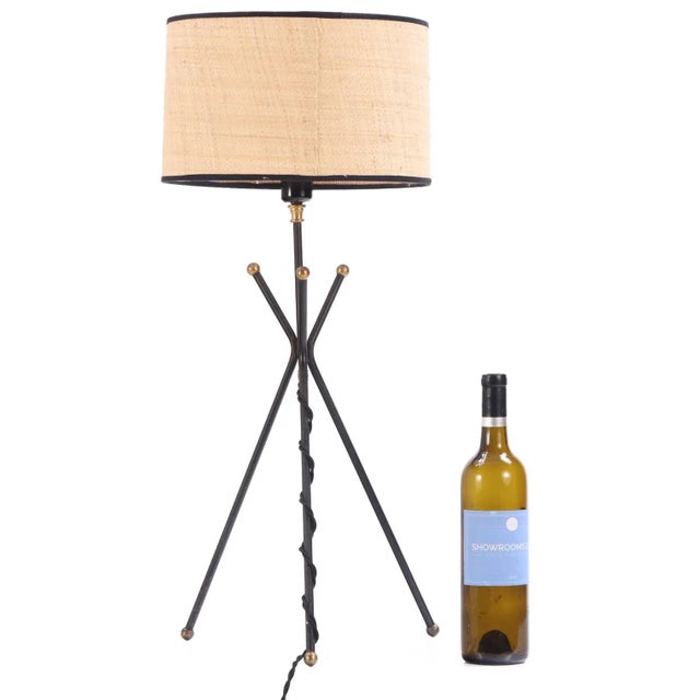 A simple standing table lamp with finely designed three-legged iron base, with each leg topped and finished with a brass...