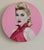 This artwork features a striking portrait of a woman set against a vibrant pink background, which enhances her classic...