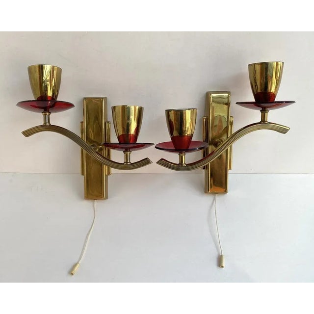 Stylish Paired wall sconces in beautiful gilt brass and ruby acrylic glass decorative elements from the German...