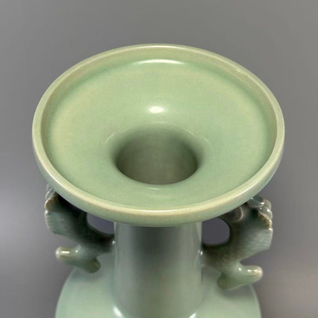 This Chinese Longquan celadon porcelain vase is equipped with a pair of exquisitely‑sculpted dragon‑form side handles. It...