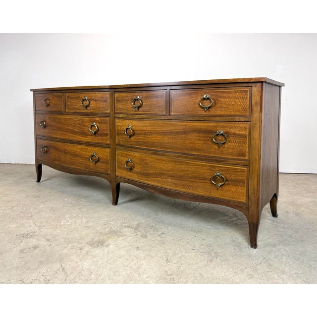 A gorgeous and high-quality Federal/Georgian-style walnut bow front chest of drawers by Baker Furniture with inlaid...