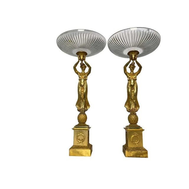 A pair of allegorical french tazzas with cut crystal bowls suspended by aphrodite figurative ladies, and standing on...