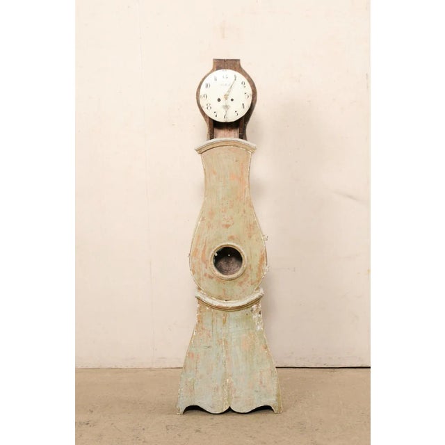 A Swedish carved wood grandfather clock from the early 19th century. This antique floor clock from Sweden features a...