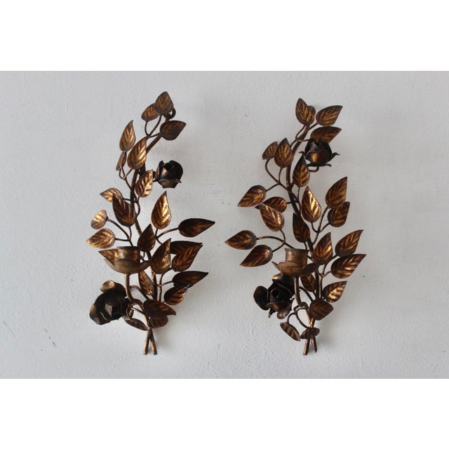 A vintage pair of brass floral wall sconces features intricate leaf and rose details, providing a classic bohemian accent...