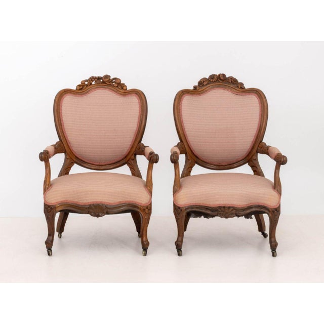 Pair of Louis XVI Style Walnut Fauteuils, each with fruit and vine crest, pink upholstered seat and oval back upon four...