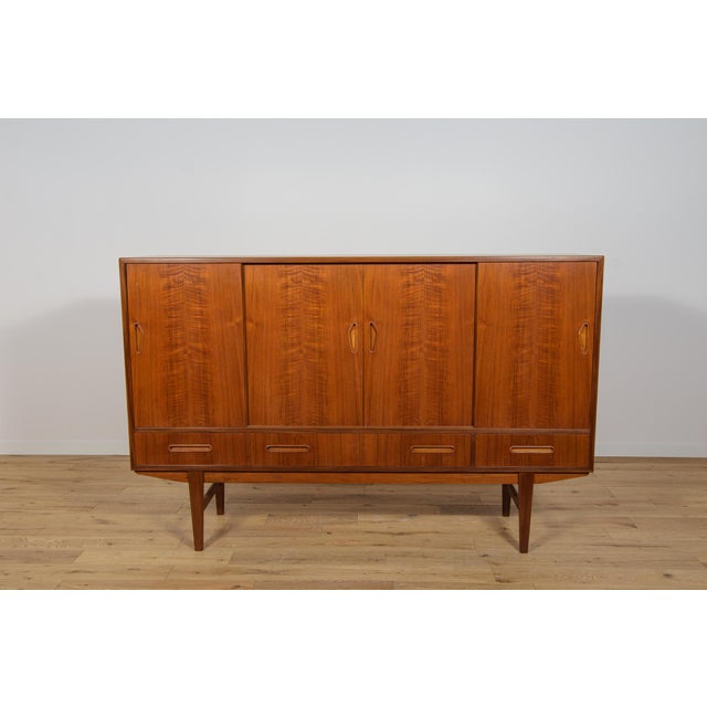 Mid century highboard manufactured during the 1960s in the Denmark. The highboard consists of four sliding doors and four...