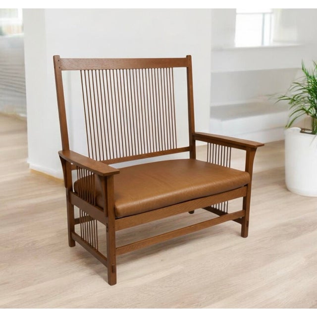 This is a genuine Stickley Oak Settee. It is a medium walnut shade with a tan leather seat. It stands just over 48” tall....