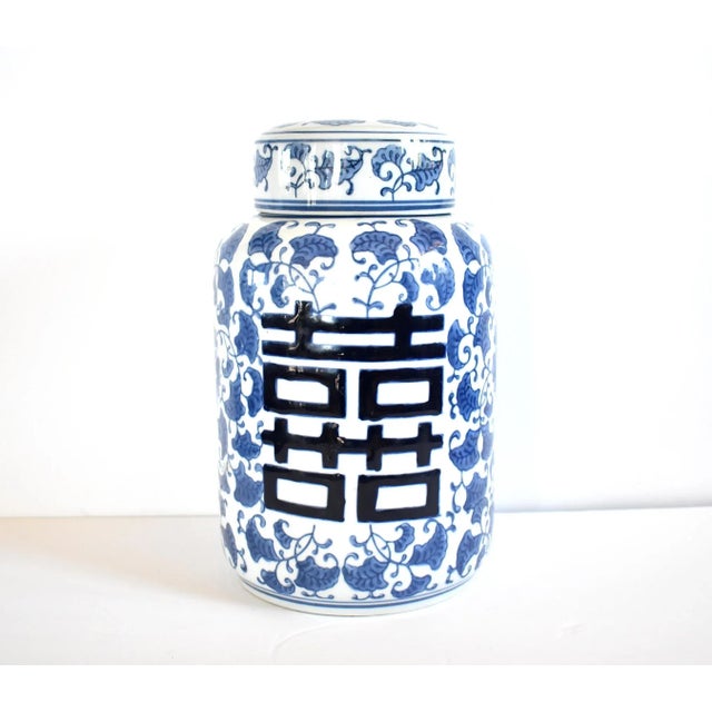 A vintage Chinese Export pottery-style ginger jar with blue underglaze designs of a vine-leaf motif and auspicious...