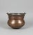 A substantial 19th-century hand-hammered copper cauldron of low, bulbous form, with a wide rolled rim and opposing iron...
