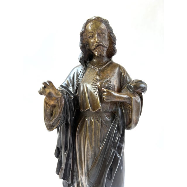 This finely crafted bronze sculpture depicts the Sacred Heart of Jesus, a revered subject in Christian iconography...
