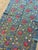 Hand-embroidered Suzani panel from Uzbekistan — red pomegranates and cream trefoil blossoms scrolling over a teal blue...