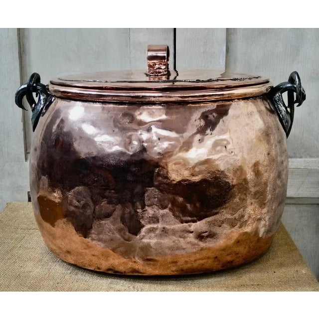 A large and highly decorative polished copper pot. Made from hammered copper with an hand forged iron swing handle. The...