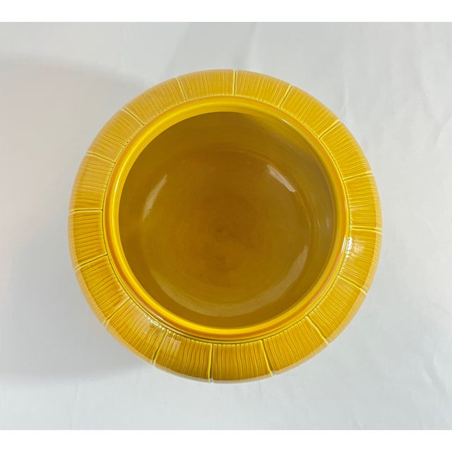 A distinguished Chinese porcelain bowl distinguished by its warm amber glaze and delicate lotus petal motif. The piece...