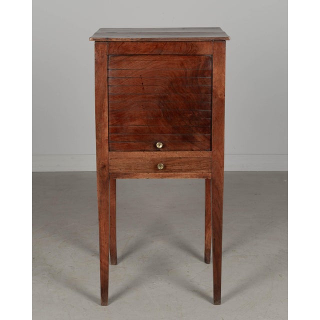 A 19th century French Country walnut side table, or nightstand, with a vertical tambour door above a slim dovetailed...
