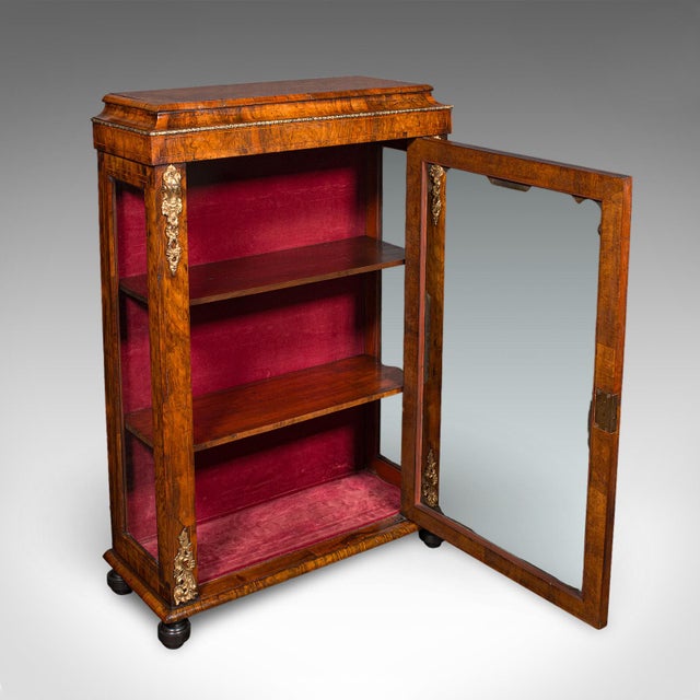 This is an antique pier cabinet. An English, walnut and ormolu glazed display or bookcase, dating to the Victorian period,...