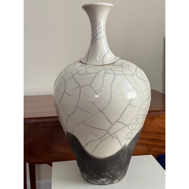 A striking 22-inch signed raku pottery vase by American ceramic artist Kerry Gonzalez, featuring an ivory crackle glaze...
