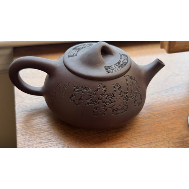 A distinctive Chinese Chaozhou zhuni red clay teapot bearing the impressed seal 章燕城制, translating to “Made by Zhang...