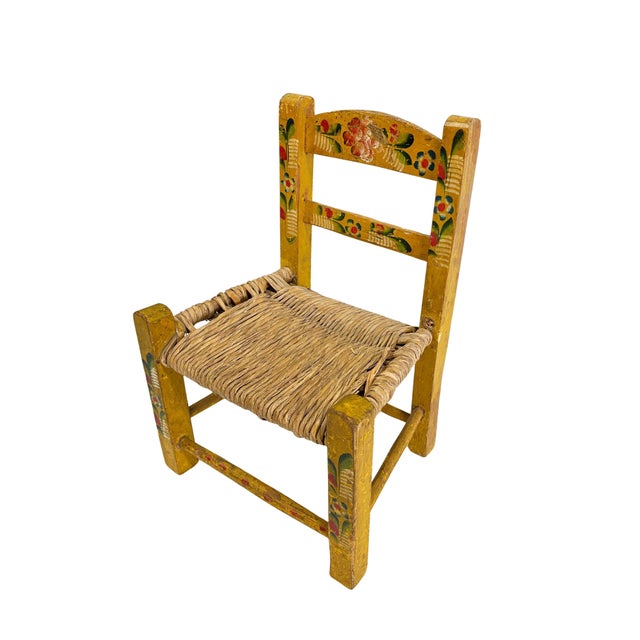 This is a vintage Mexican folk art children's chair. The bright, hand-painted chair has a floral theme with wooden frame...