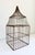 A charming decorative wirework birdcage featuring a tiered pagoda-style dome top and a weathered brown-bronze painted...