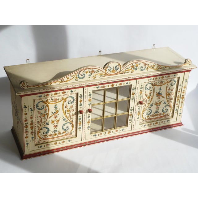 A stunning vintage wooden display cabinet hand painted with a beautiful technique called Hindeloopen and it is also...