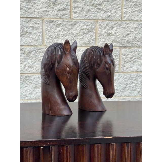 A handsome pair of vintage carved wooden horse head sculptures featuring expressive profiles, finely detailed manes, and...