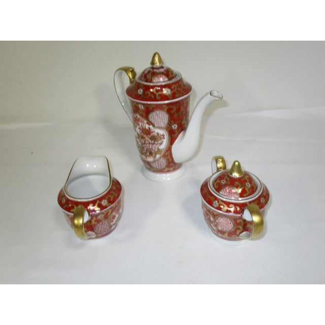 A Japanese Gold Imari porcelain tea service consisting of a tea pot, sugar and creamer. It is hand-painted in colors of...