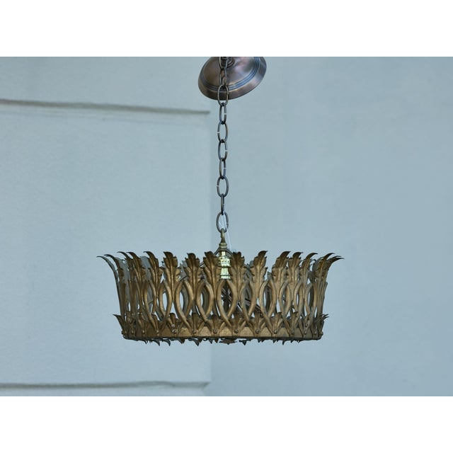 A Spanish gilt metal crown chandelier from the Midcentury period, with elongated leaves and frosted glass bottom. Created...