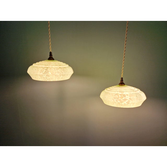 Pair of Art Deco pendant lights in light green speckled glass, 1930s. Each pendant has been rewired with a beige twisted...