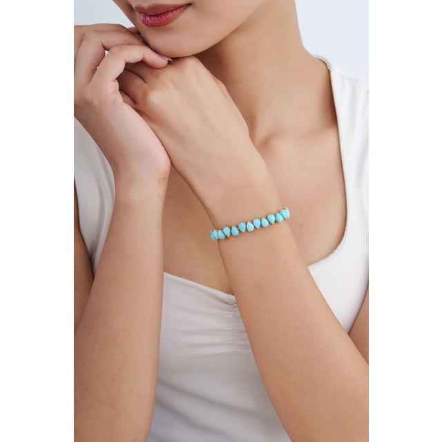 This statement tennis bracelet showcases 19.77 carats of natural pear-cut cabochon turquoise, set in 14k yellow gold. Each...