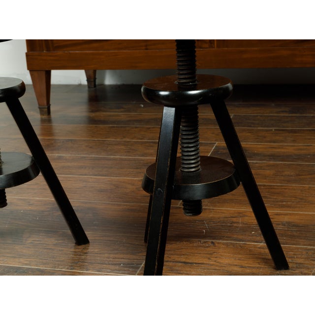 A pair of American adjustable artist's stools from the early 20th century, with black finish. Made in the USA during the...