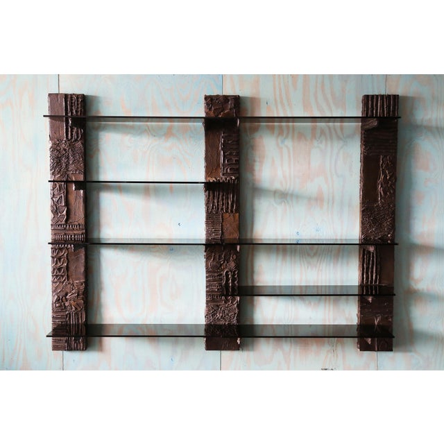 A Paul Evans wall unit book shelf in bronzed resin and glass. This unit featuring eight smoked glass shelves and three...