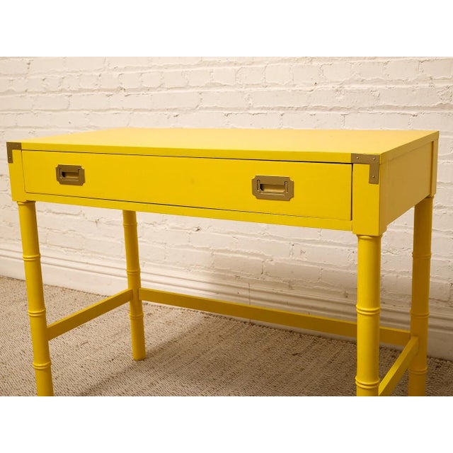 A fantastic vintage writing desk with a bold lacquered yellow finish and a playful mix of Hollywood Regency and campaign-...
